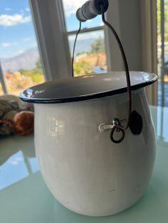 a white pot sitting on top of a table next to a pair of scissors and a window