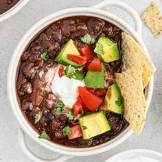 a white bowl filled with black bean chili and avocado