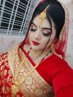 a woman wearing a red and gold bridal outfit, with her eyes closed to the side