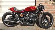 a red and black motorcycle parked in front of a brick building next to a garage