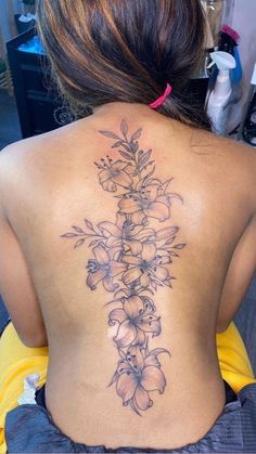 a woman's back tattoo with flowers on it