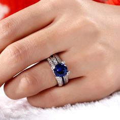 a woman's hand with two rings and a blue stone on the ring finger