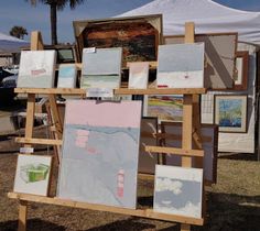 an easel with paintings on it in front of a tent