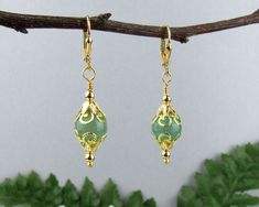 "I created these Wonderful Victorian Style dangle earrings with Green Aventurine Gemstone Beads surrounded by golden beads and beautiful filigree bead caps.   The Genuine Green Aventurine beads are a beautiful true \"jade green\" color and what shows as darker flecks in the pictures are not at all discernible in person - the green is very solid and pure. The bright golden tones of the metal beads create a stunning contrast to the soft green. These are truly beautiful earrings and will work for d Gold Aventurine Beaded Jewelry, Gold Aventurine Earrings Gift, Victorian Style Earrings, Jade Green Color, Golden Beads, Head Pins, Red Crystals, Style Earrings, Bead Caps