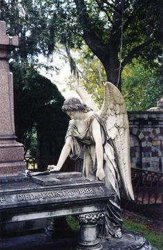 an angel statue sitting on top of a stone bench