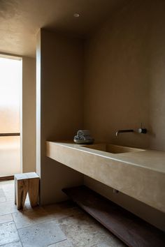 a bathroom with a large sink and wooden bench next to the bathtub in front of a sliding glass door