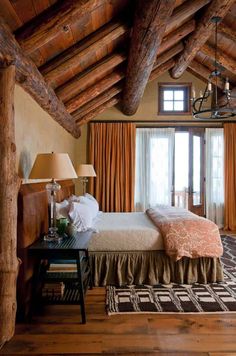 a large bed sitting under a wooden ceiling next to a window in a living room