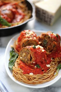 spaghetti with meatballs and spinach on a white plate