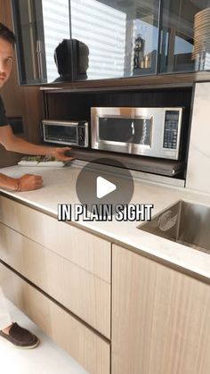 a man standing in front of a kitchen counter next to a microwave oven and sink