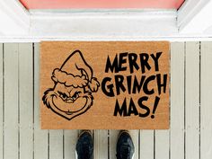 a door mat with the words merry grinch mas on it next to a pair of black shoes