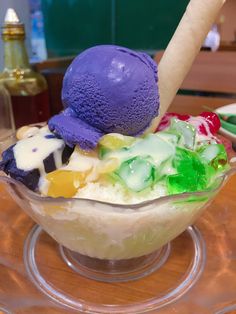 an ice cream sundae with colorful toppings in a glass bowl on a table