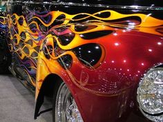 an old car with flames painted on it's hood and the front grills