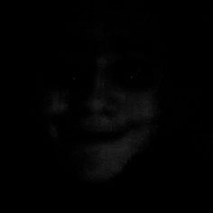 a black and white photo of a person's face in the dark