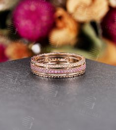 a stack of three rings sitting on top of a table next to some pink flowers