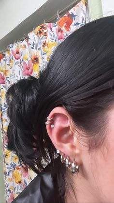 a woman with black hair wearing ear piercings