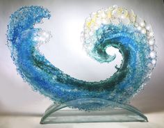 an artistic glass sculpture made to look like a wave with pearls on the top and bottom