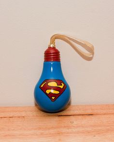 a blue light bulb with a superman logo painted on the side and a brown string hanging from it