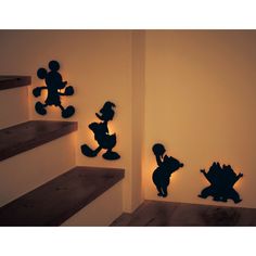 the silhouettes of mickey mouse and pooh are on the wall next to some stairs