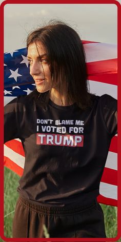 This image is a woman standing in a grass field, holding an American flag across her back. She's wearing a black shirt which reads, "Don't blame me, I voted for Trump" Don't Blame Me, Reality Check, Cute Tshirts