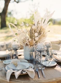 the table is set with plates, silverware and flowers in vases on it