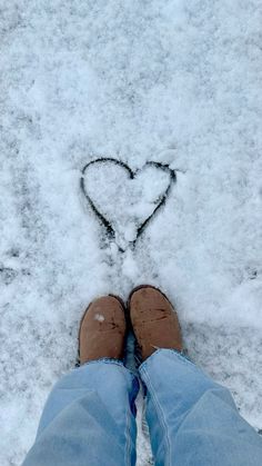 someone is standing in the snow with their feet up and there is a heart drawn in the snow