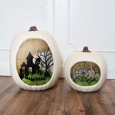 two white pumpkins decorated with halloween scenes