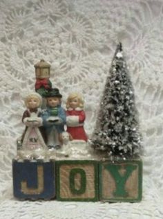 a small christmas tree and toy blocks with the word joy spelled out in front of it