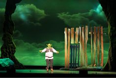 a man standing on top of a stage next to wooden poles