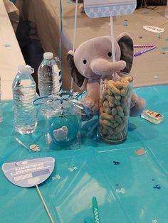 an elephant is sitting on the table with some candy in it's trunk and water bottle