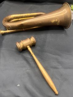 an old brass pipe and a wooden mallet on a black tablecloth covered surface