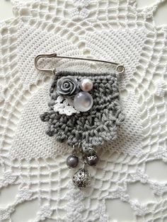 a close up of a brooch on a doily with beads and flowers in it