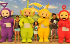 people in costumes posing for a photo with the teletubistes at an amusement park