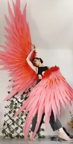 a woman in black shirt holding large pink bird wings