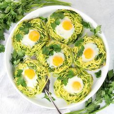 an overhead view of spaghetti with eggs and parsley in the middle on a white plate