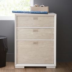 a white chest of drawers next to a window