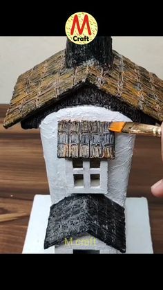 someone is painting the roof of a small house with paintbrushes and paper machs