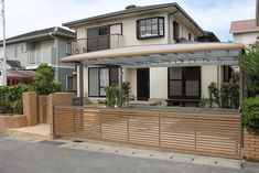 a house with a wooden fence in front of it and some bushes on the side