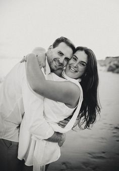 a man and woman hugging each other on the beach