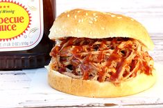 a bbq sandwich next to a bottle of barbecue sauce