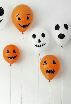 halloween balloons with faces and numbers hanging from strings in front of a white wall that says trick or treat