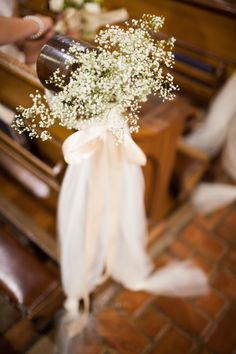 a bouquet of baby's breath sits in front of the pews at a wedding