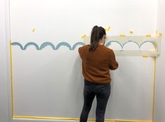 a woman standing in front of a white board with blue and yellow waves on it