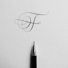 the letter f is written in cursive writing on white paper with a fountain pen