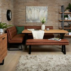 a living room filled with furniture and a wooden table in front of a brick wall