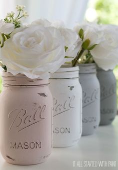 three painted mason jars with flowers in them