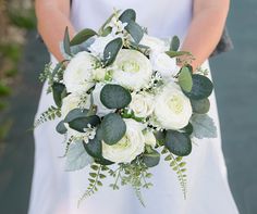 a bride holding a bouquet of white flowers