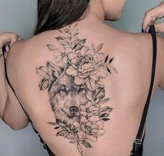 a woman's back with a wolf and flowers on it