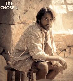 a man sitting on top of a wooden bench next to a stone wall with the words, the chosen