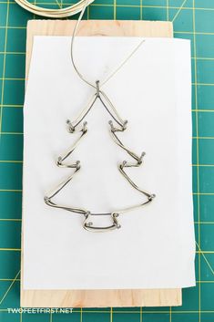 a christmas tree made out of metal wire sitting on top of a piece of paper