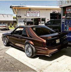 a brown car parked in front of a gas station next to a blue and white truck